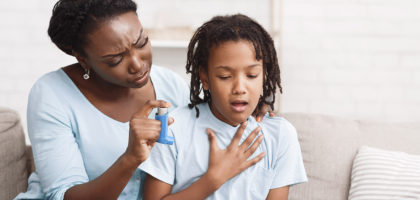 Mother holding asthma inhaler for daughter